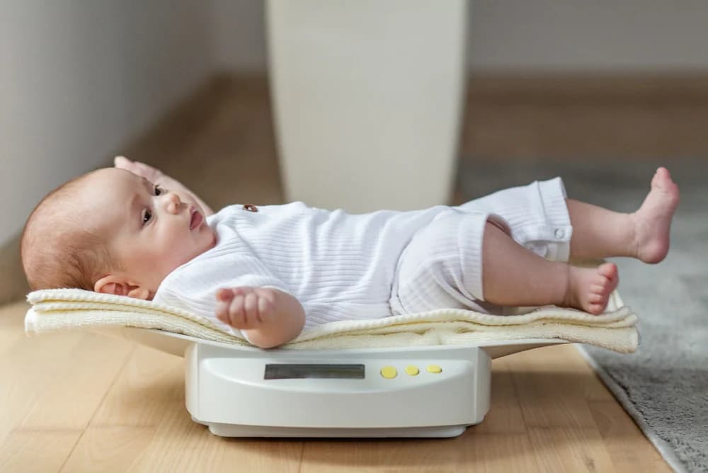 sağlık kontrolü veya ağırlık kontrolü için dijital bebek terazisinde yatan sevimli bebek