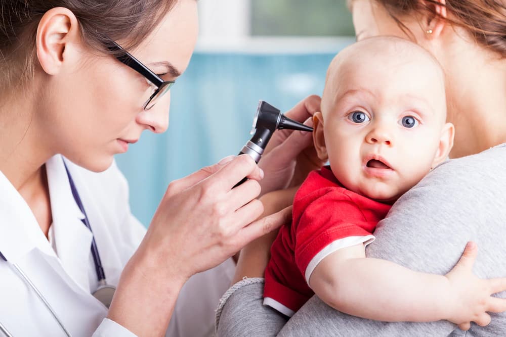 doktor ortakulak iltihabı ihtimali olan bebeği otoskop ile muayene yapıyor