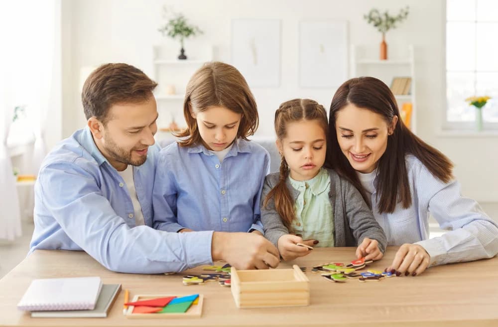 Anne, baba ve iki çocuk birlikte ahşap yapboz yapıyor — 3-6 yaş için eğitici oyuncak önerileri