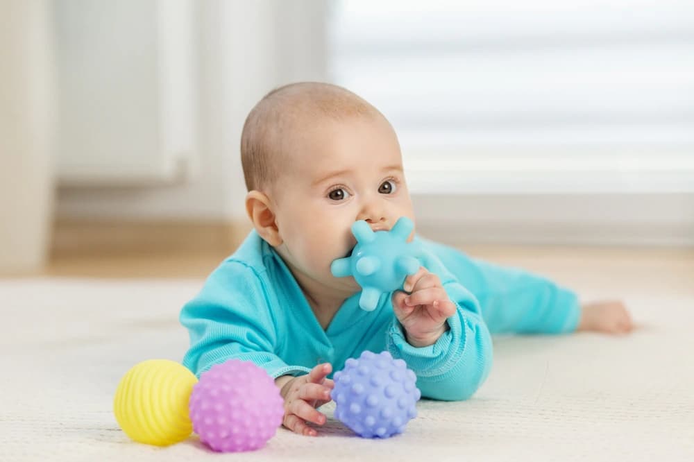 oyuncaklarla yerde vakit geçiren infant dönemindeki bebek