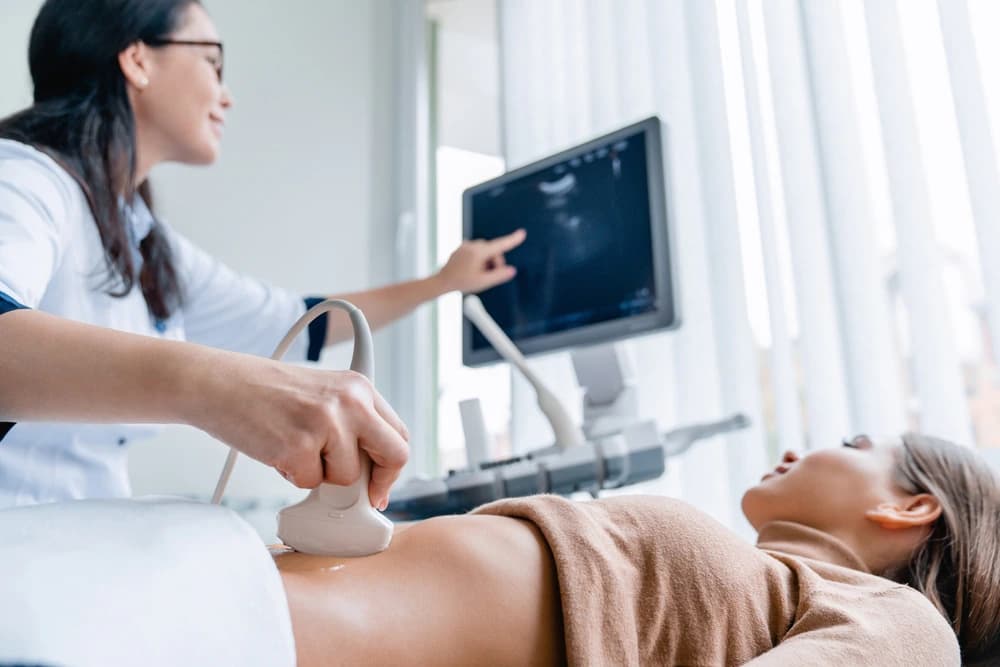 hamilelik takibi sırasında ultrason kontrolü yapılan anne adayı ve ekrandaki bebeği gösteren doktor
